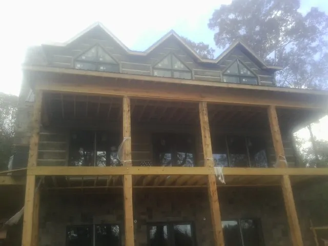 Dormers and porch framing on a large log home under construction — Roof Coating work by our crew in Reston