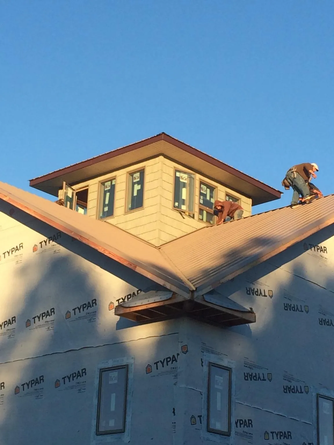 Roofers working around a rooftop cupola on a new metal roof at sunset — Roof Waterproofing in Reston by Roofing Brothers